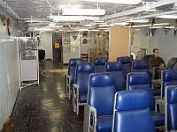 There is a single row of chairs behind a glass wall with three pilots getting their briefing from the fourth guy standing.  The